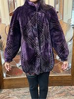 Front view of coat on model showing stand collar, snap closure, geometric pattern