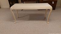 Photo of the cream colored console table showing front and side, ribbed leg design and curved feet visible