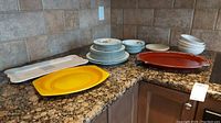 Wide view of all dishes arranged on counter including Evesham Vale plates and bowls, Denby bowls, and three serving platters.