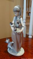 Front view of the Lladro figurine showing a girl holding multiple cats with one cat climbing her skirt.