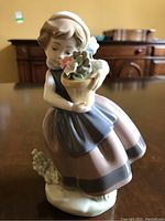 Front view of the Lladro figurine showing a young girl holding a flowerpot with flowers.