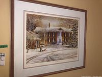 Framed print featuring a winter scene with a brick house and snow-covered yard with children playing, hung on a wall.