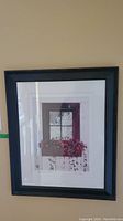 Framed signed print hung on wall showing a window with flowers on the windowsill.