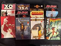 A collection of 12 comic books, a mix of trade paperbacks and hardcovers, neatly arranged showing front covers. Various titles including Red Sonja, Kitty Pryde, New Mutants, Spider-Woman, and others.