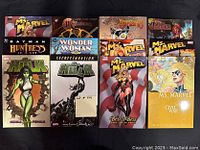 Top-down image of 12 trade paperback and hardcover comic books arranged in a grid, showing covers with superheroes such as Ms. Marvel, Hulk, Batman, Wonder Woman, and more.