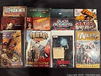 Photo of 12 assorted TPB and hardcover comic and graphic novels.