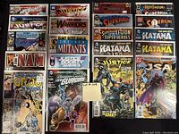 Photo showing 20 different high grade comic books bagged and boarded. Includes notable titles such as Justice League of America, New Warriors, The 'Nam, Groo, Justice Society of America, Green Lantern, Batman, Superboy, Katana, Supergirl, and JSA.