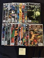 Photo showing 20 DC comic books arranged in two rows, featuring characters including Justice League of America, Justice Society of America, Batman, Superman, Wonder Woman, Flash, and Martian Manhunter. Comics are bagged and boarded.