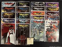 Photo displaying 20 high grade Batman comics arranged in 4 rows, each comic individually bagged and boarded, with visible comic covers showing Batman Eternal title and various characters including Batman, Catwoman, Batgirl, and Penguin.