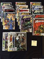 Photo showing 20 bagged and boarded comic books with Robin and JLA titles.