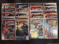 Photo showing 20 Superman comics in excellent condition, bagged and boarded in clear protective sleeves, arranged in rows displaying colorful cover art with various Superman characters and storylines.