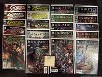 Photo showing all twenty comic books arranged in four rows, bagged and boarded with visible issues of Injustice, multiple Green Arrow, Frankenstein, Batman, and Harley Quinn comics.