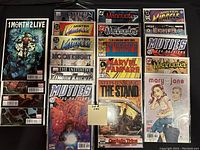 Top down view of 20 bagged and boarded comic books in two columns, featuring covers of 1 Month 2 Live, Stephen King The Stand, multiple Mister Miracle and Manhunter issues, Moon Knight, Muties, Marvel Fanfare, Mindhunter, and Mary Jane.