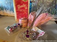 Set of Barbie holiday tree decorations, including pink feather branches, purple and pink ornaments, a tiara tree topper, and original Barbie box.