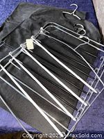 Black fabric closet organizer and multiple chrome metal hangers with plastic grips on a blue surface