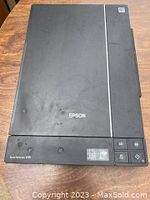 Top view of black Epson Perfection V37 flatbed scanner showing controls and logo.