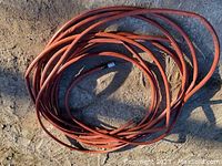 Orange heavy duty water hose coiled on the ground showing length and material.