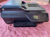 HP OfficeJet 4620 all-in-one printer showing device from front angle on pink textured surface.