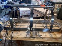 Chrome oval ceiling pot rack with three integrated light sockets. Two large suspenders and wiring visible for electrical connection.