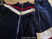 Navy blue velour zip-up jacket and matching pants with red and white stripes on jacket.