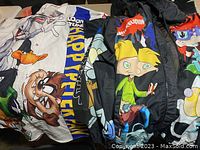 Multiple teen girls clothing items spread out showing various cartoon prints including Taz, Hey Arnold!, and characters from Rugrats in a variety of colors and styles.