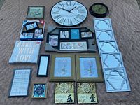 Full view of the lot laid on a textured surface showing all wall art items including clocks, frames, and plaques.