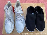 Pair of men's white high-top lace-up sneakers with gold emblem and black slip-on knit sneakers.