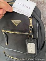 Close-up of Ellen Tracy tag held next to backpack showing brand authenticity and condition new with tag