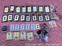 All electrical plate covers, outlet covers, drawer knobs, and packaged doorbells laid out on fabric