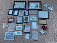Multiple picture frames of different sizes and styles laid out on the floor