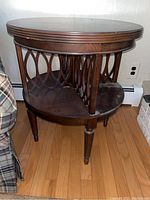 Side angle view of the round table showing carved lattice wood side panels and tapered legs supporting top and shelf.