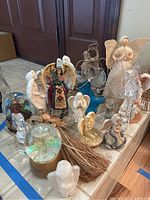 Overall view of angel figurine assortment showing various materials and styles, including snow globe and fabric wings.