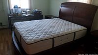 Full view of wooden bed frame with mattress placed on it, showcasing the size and design.
