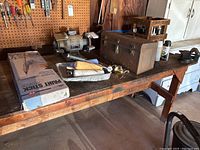 Workbench surface holding metal toolbox with hand tools, paint stick kit, caulk, and wooden toolbox with woodworking tools