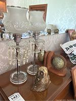 Pair of lamps with frosted glass shades, crystal prisms, and two wooden globe bookends on a wooden surface.