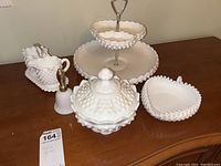 Lot showing all items on a table: two-tier serving caddy, covered candy dish, cream and sugar set on tray, heart dish, bell-shaped piece