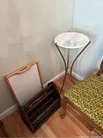 Full view of the three items: plant stand with stone top, wooden lap tray, and dark wooden magazine rack near a chair