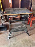 Full view of the Black & Decker Workmate 550 portable project center workbench showing the frame and top surface with orange clamps attached.