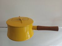 Side view of vintage yellow Dansk Kobenstyle pot with teak handle and lid showing shape and handle detail.
