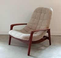 Side view of chair showing curved teak frame and oatmeal fabric upholstery.