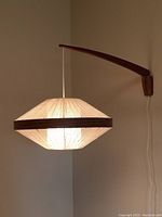 Lamp mounted on wall, illuminated, showing shade shape and light diffusion