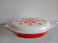 Side view of the vintage Pyrex divided casserole dish with red bottom and white lid featuring floral Friendship pattern.