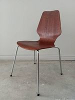 Side front view of vintage bent ply teak chair with chrome legs showing wood grain and leg structure.