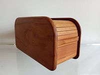 Side view of teak tambour roll top storage box; shows curved edges and slatted roll top with handle.