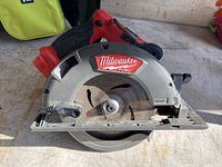 Red and black Milwaukee cordless circular saw with visible blade and branding on side.