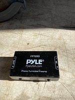 Black rectangular Pyle PP999 Phono Turntable Preamp box on a surface with visible input and output ports on sides.