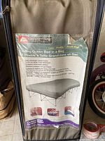 Photo of the Ozark Trail brand folding queen bed in a bag label on its storage bag, detailing features and dimensions.
