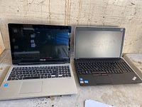 Photo of two laptops side by side: silver Asus SonicMaster with cracked screen on the left, black Lenovo ThinkPad on the right