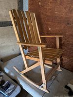 Wooden rocking chair fully set up showing slatted back and seat, armrests, and curved rocker base.