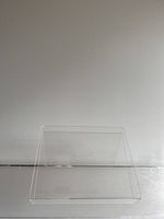Front view of clear acetate book stand against white wall on clear surface.